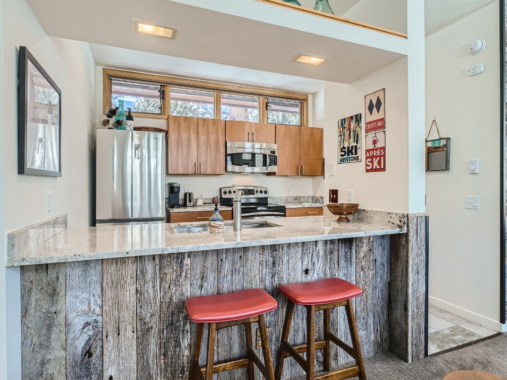 2017 Soda Ridge Road, Unit 1939 Keystone, CO 80435 - Photo 8 of 27 a kitchen with granite countertop a dining table chairs cabinets a stove and a window