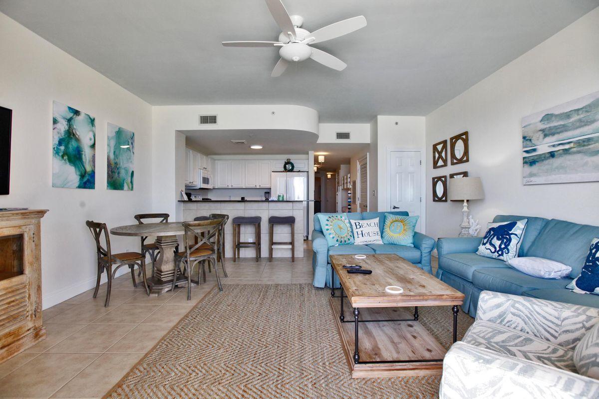 15817 Front Beach Road, Unit 407W Panama City Beach, FL 32413 - Photo 5 of 23 a living room with furniture a rug and a dining table