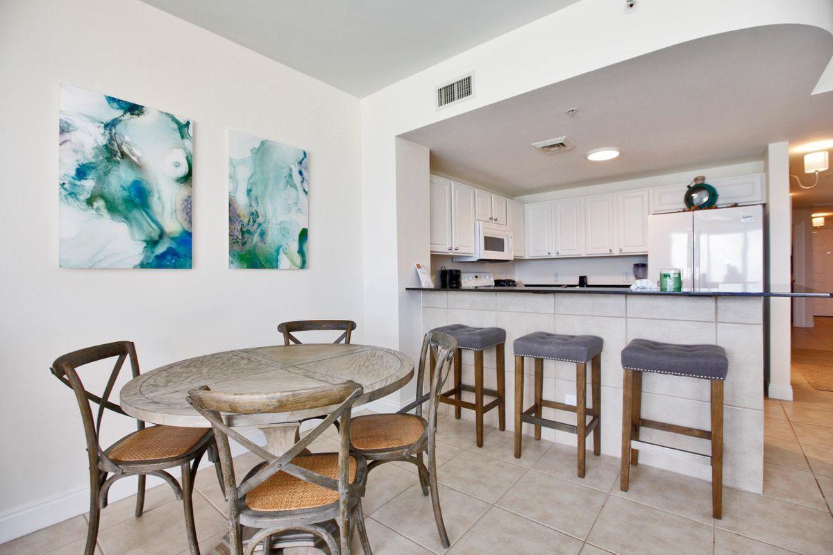 15817 Front Beach Road, Unit 407W Panama City Beach, FL 32413 - Photo 6 of 23 a kitchen with stainless steel appliances kitchen island granite countertop a dining table chairs and a refrigerator