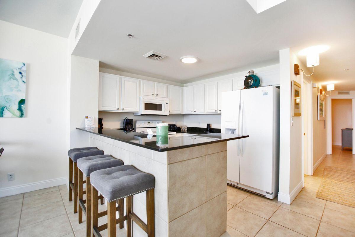 15817 Front Beach Road, Unit 407W Panama City Beach, FL 32413 - Photo 7 of 23 a kitchen with stainless steel appliances a refrigerator sink and cabinets