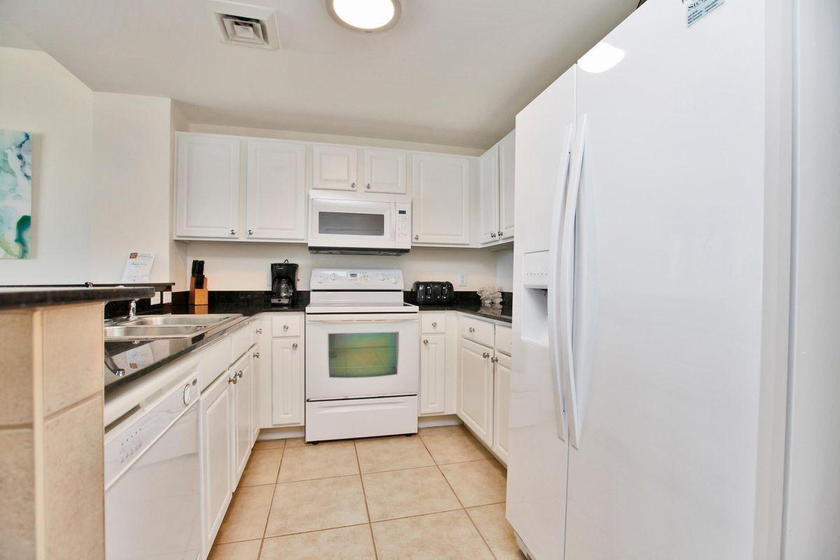 15817 Front Beach Road, Unit 407W Panama City Beach, FL 32413 - Photo 8 of 23 a kitchen with white cabinets and white appliances