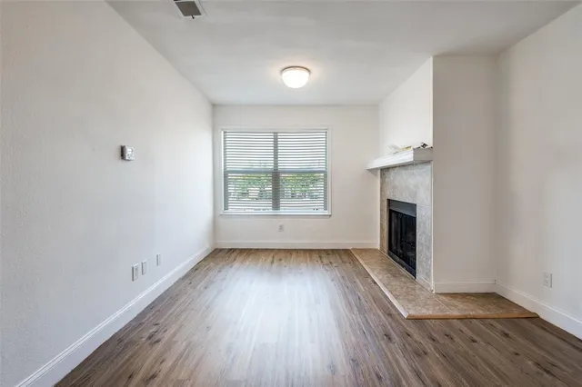 an empty room with wooden floor a fireplace and windows