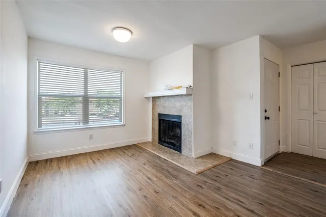 an empty room with wooden floor a fireplace and windows