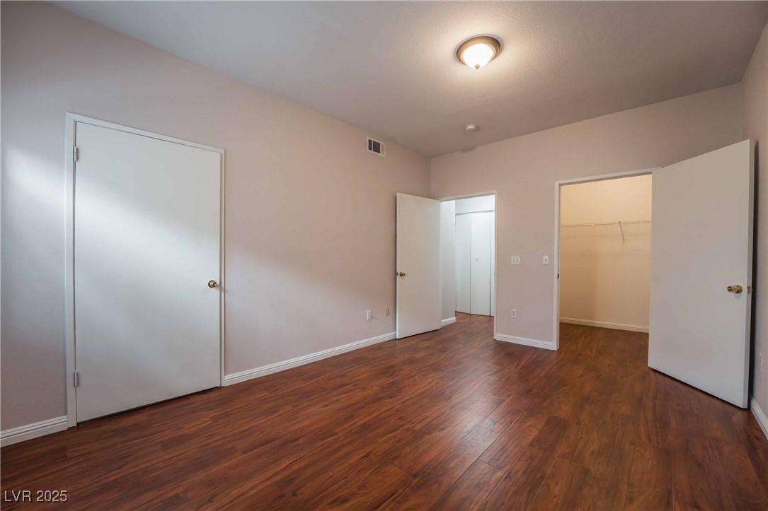 5415 West Harmon Avenue, Unit 1162 Las Vegas, NV 89103 - Photo 15 of 21 Unfurnished bedroom featuring a spacious closet and dark wood-style floors