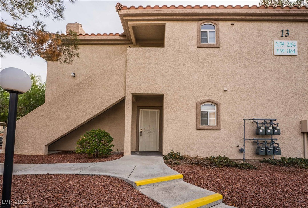 5415 West Harmon Avenue, Unit 1162 Las Vegas, NV 89103 - Photo 3 of 21 View of front of property with a tile roof, stucco siding, a chimney, and stairs