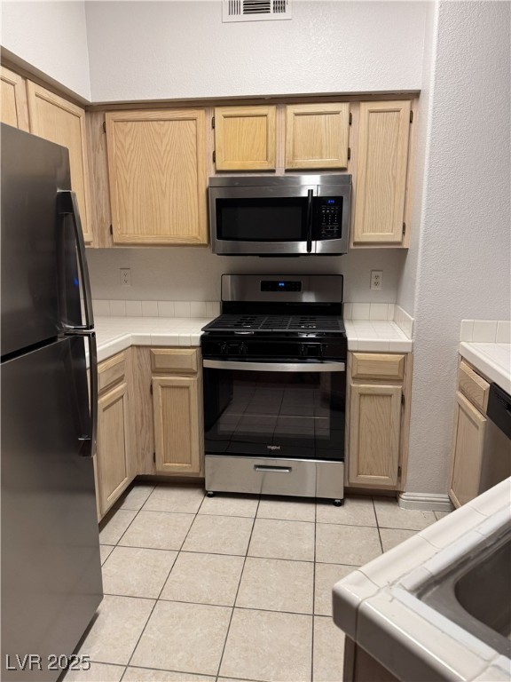 5415 West Harmon Avenue, Unit 1162 Las Vegas, NV 89103 - Photo 6 of 21 Kitchen with tile counters, stainless steel appliances, light brown cabinetry, a textured wall, and light tile patterned floors