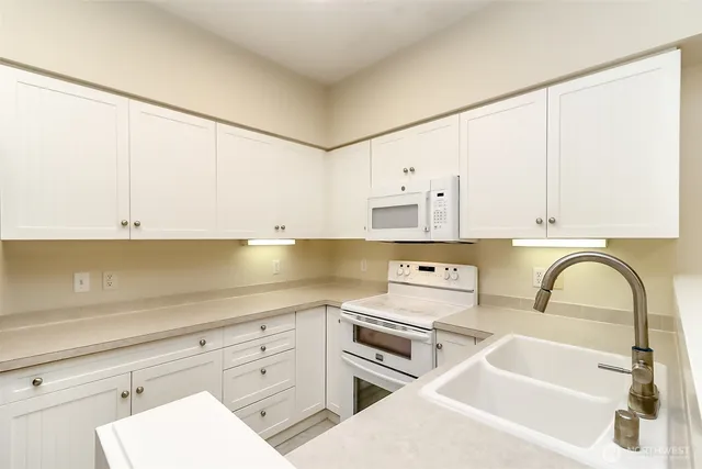 a kitchen with stainless steel appliances a sink a stove and white cabinets
