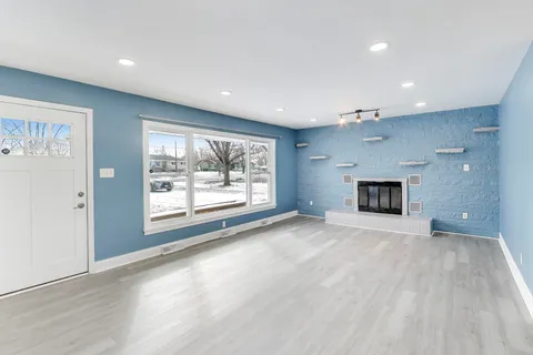 a view of an empty room with a window and fireplace