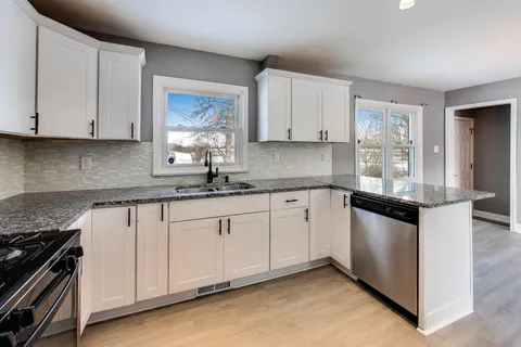 a kitchen with granite countertop white cabinets and white appliances
