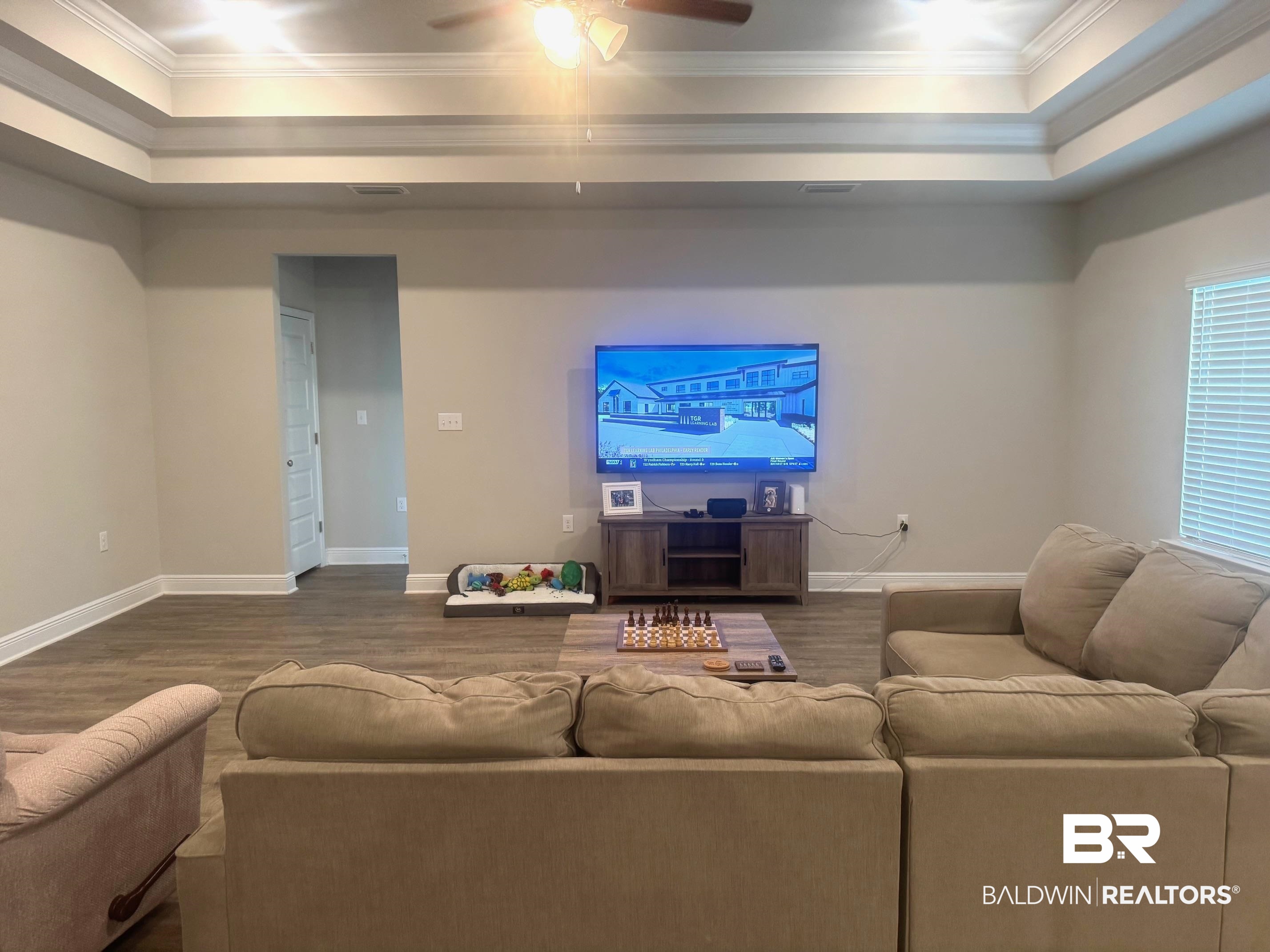 24903 Spectacular Bid Loop Daphne, AL 36526 - Photo 5 of 37 Living area with crown molding, a tray ceiling, dark wood-style flooring, and a ceiling fan