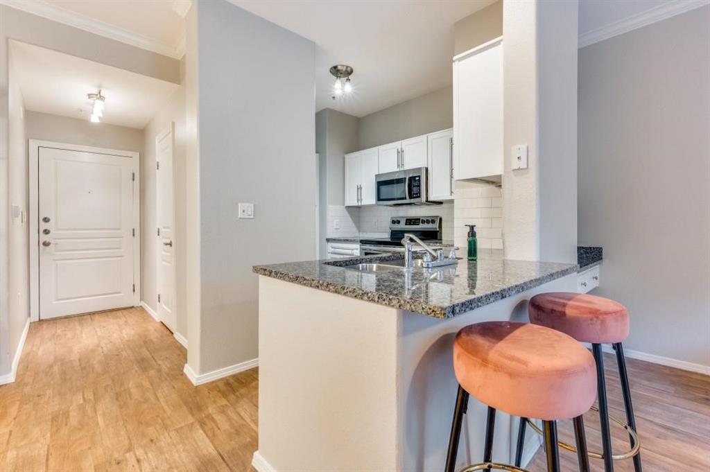 330 Las Colinas Boulevard East, Unit 140 Irving, TX 75039 - Photo 2 of 14 a kitchen with stainless steel appliances a dining table chairs and a refrigerator