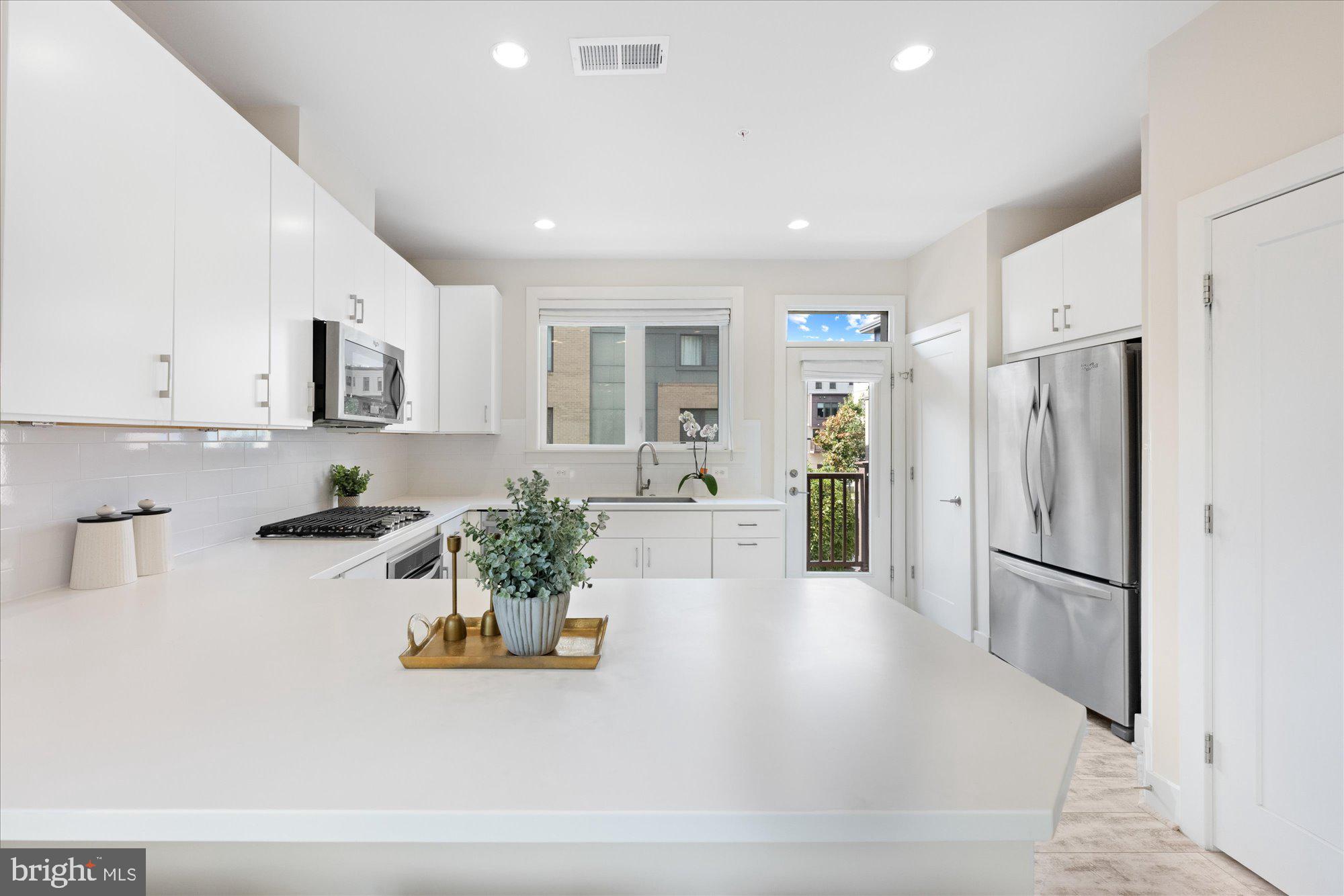 6597 Rock Spring Drive Bethesda, MD 20817 - Photo 8 of 37 a large white kitchen with stainless steel appliances a refrigerator a stove a microwave and cabinets