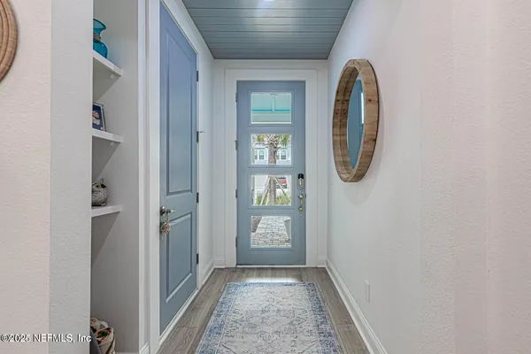 a view of a hallway with wooden floor and a bathroom