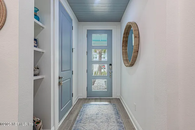 a view of a hallway with wooden floor and a bathroom