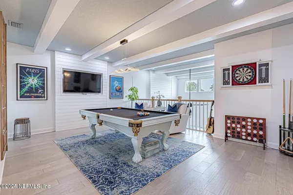 a living room with furniture pool table flat screen tv and a window