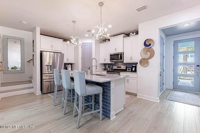 a kitchen with granite countertop a refrigerator a stove a dining table and chairs with wooden floor