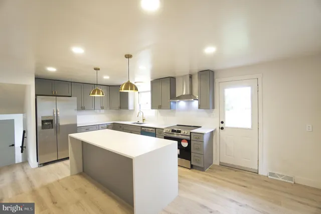 a kitchen with stainless steel appliances a sink a stove a refrigerator cabinets and a kitchen island