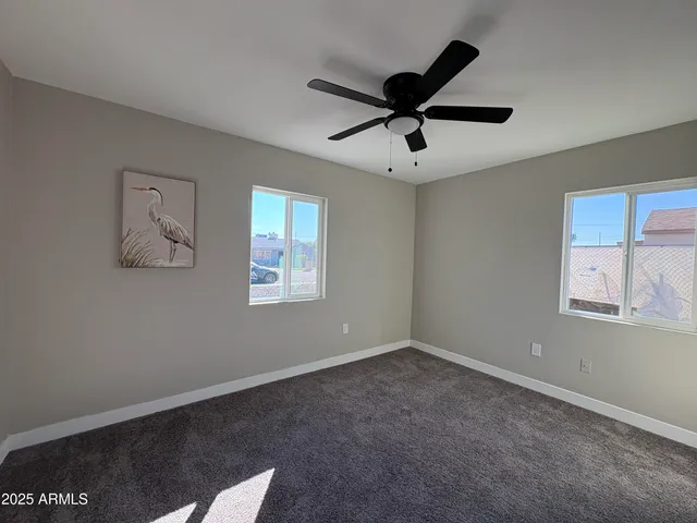 a view of a big room with a ceiling fan and windows