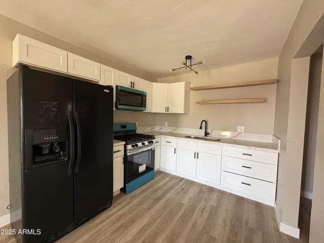 a kitchen with granite countertop a refrigerator stove top oven and sink