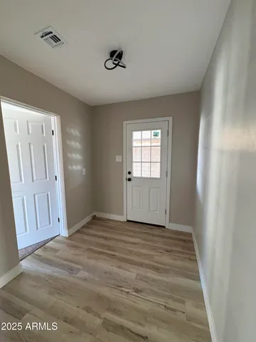 a view of an empty room with wooden floor and a window