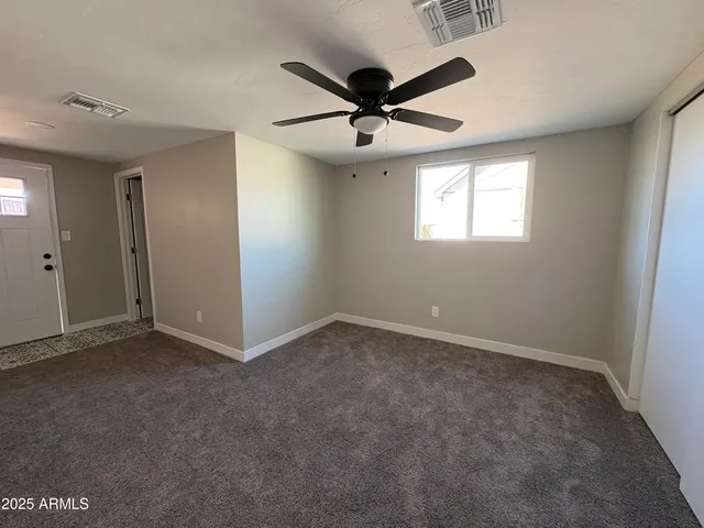 an empty room with ceiling fan and windows