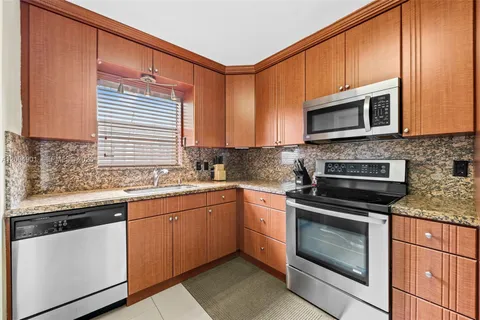 a kitchen with stainless steel appliances granite countertop wooden cabinets stove a sink and a microwave