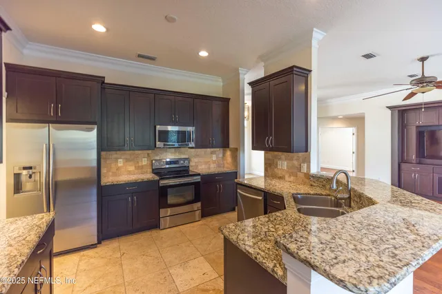 a kitchen with granite countertop a sink refrigerator stove and microwave