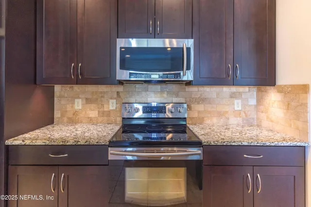 a kitchen with granite countertop wood cabinets and a stove top oven