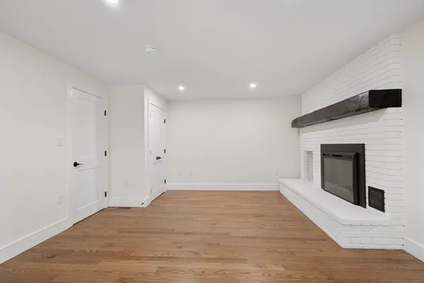 a view of empty room with wooden floor and fireplace