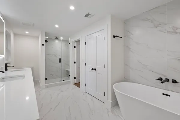 a bathroom with a tub a sink a shower and a mirror
