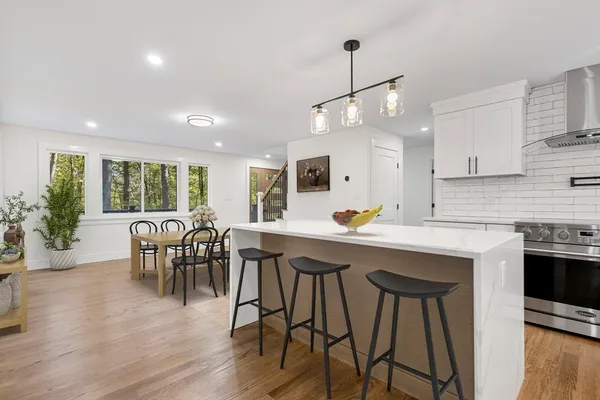 a kitchen with stainless steel appliances granite countertop wooden floor dining table and chairs