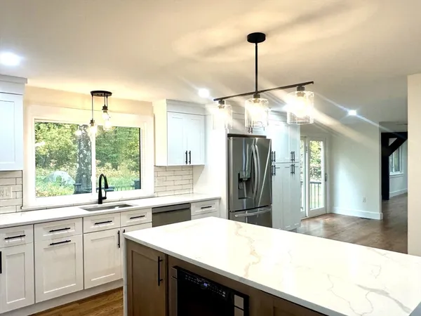 a kitchen with stainless steel appliances kitchen island granite countertop a sink and a refrigerator