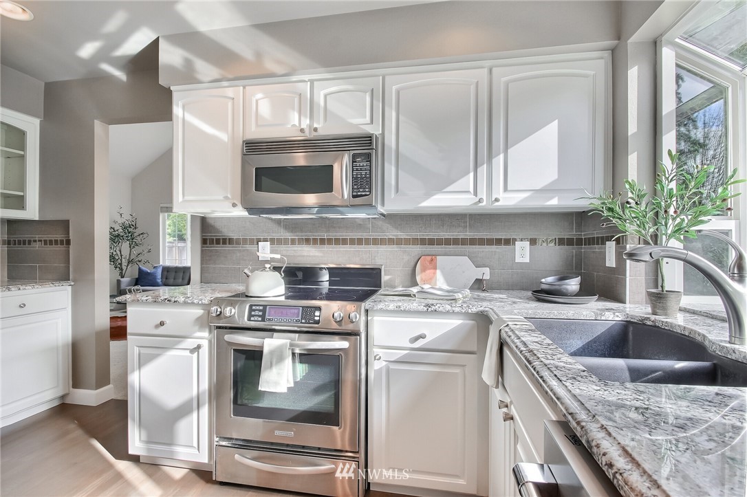 4405 Northeast 7th Street Renton, WA 98059 - Photo 11 of 27 a kitchen with granite countertop a sink stove and cabinets