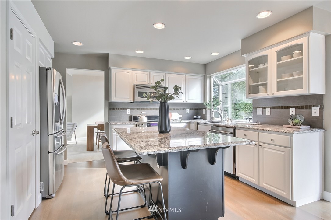 4405 Northeast 7th Street Renton, WA 98059 - Photo 8 of 27 a kitchen with stainless steel appliances granite countertop a dining table chairs refrigerator and sink