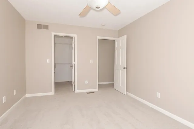 an empty room with closet and a ceiling fan