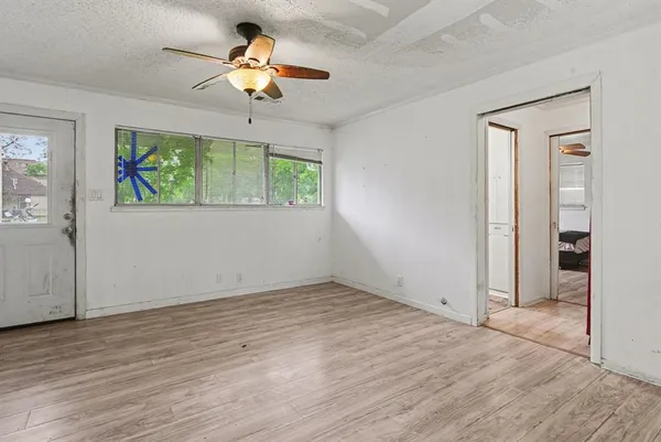 an empty room with wooden floor chandelier fan and windows