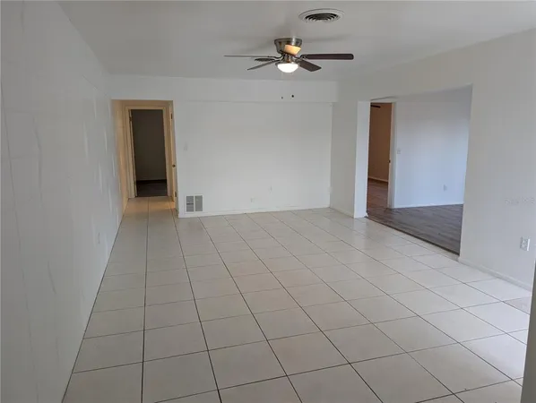 a view of an empty room with a chandelier fan