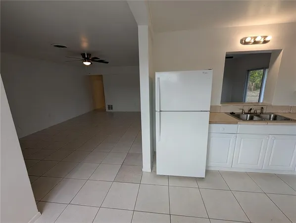 a view of kitchen with a sink refrigerator and cabinets