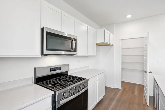 a kitchen with stainless steel appliances a white cabinets and a stove top oven