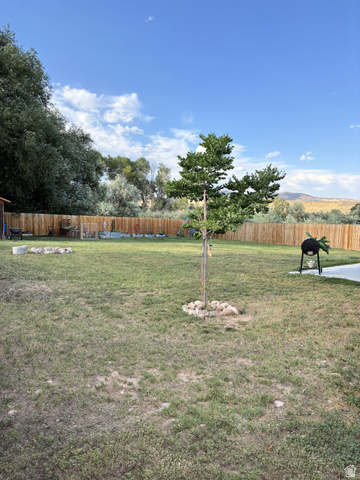 547 East 2000th Street North Vernal, UT 84078 - Photo 48 of 50 Expansive backyard with a full privacy fence, mature trees, and a tree encircled by natural stones