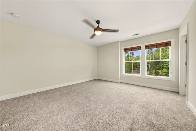 an empty room with a window and ceiling fan