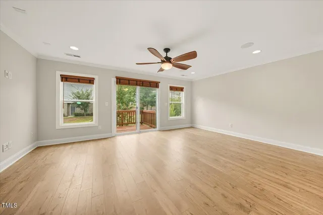 a view of an empty room with a window and wooden floor