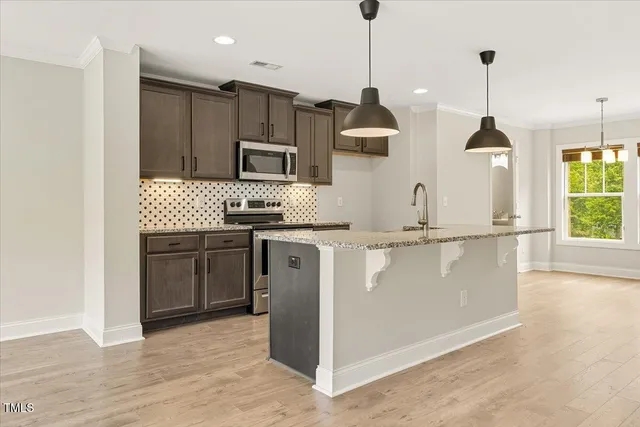 a kitchen with kitchen island granite countertop a sink a counter space appliances and cabinets