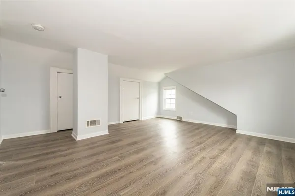 an empty room with wooden floor & windows and bathroom