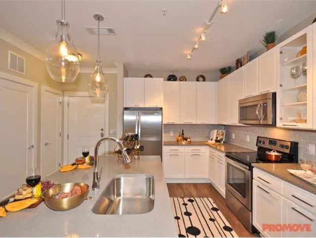 a kitchen with stainless steel appliances a sink a stove a refrigerator and cabinets