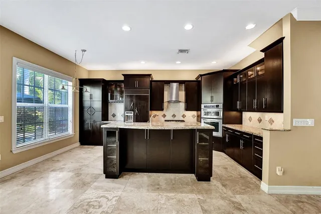 a kitchen with stainless steel appliances kitchen island granite countertop a refrigerator and a wooden cabinets