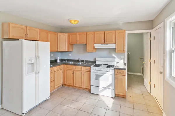a kitchen with granite countertop a refrigerator and a stove top oven