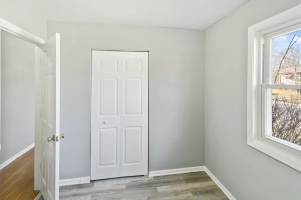 a view of an empty room with window and wooden floor