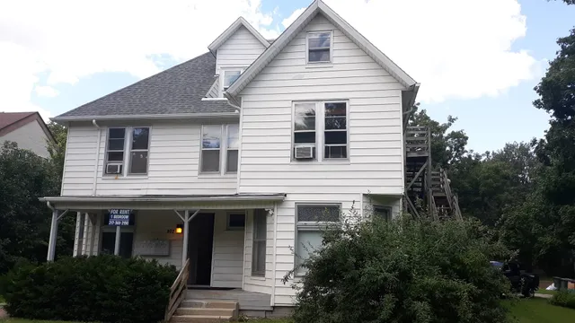 a view of a white house next to a yard