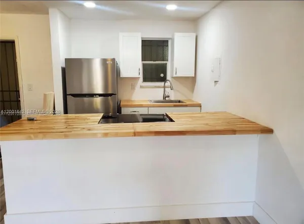 a view of kitchen with refrigerator stove and wooden cabinets
